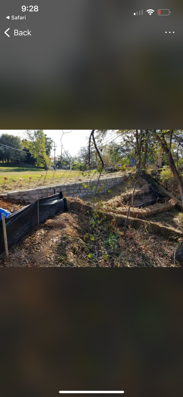 A phone screen shows a picture of a dirt field with trees in the background.