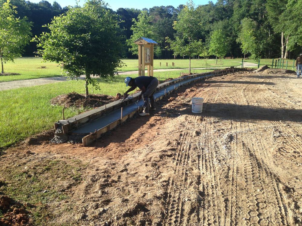 A man is laying concrete on a dirt road