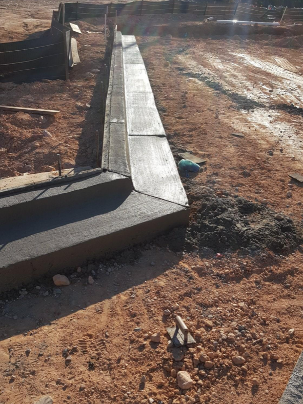 A concrete wall is being built in a dirt field
