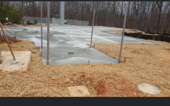 A concrete floor is being built in a field with trees in the background.