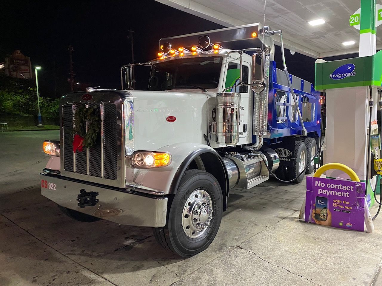 A large semi truck is parked at a gas station at night.