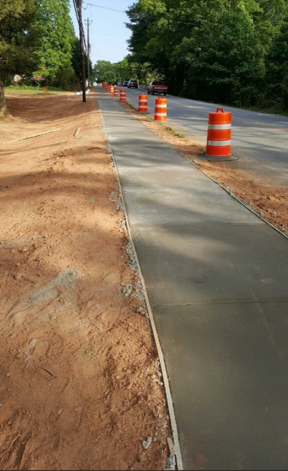 A concrete sidewalk is being built next to a dirt road.