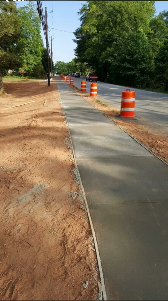 A concrete sidewalk is being built next to a road.