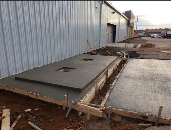 A concrete walkway is being built in front of a building