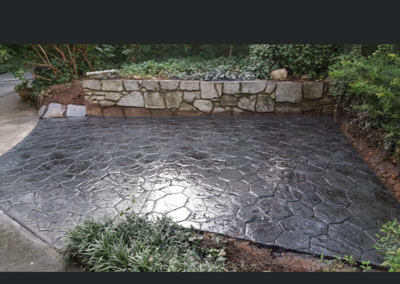 A concrete patio with a stone wall in the background.