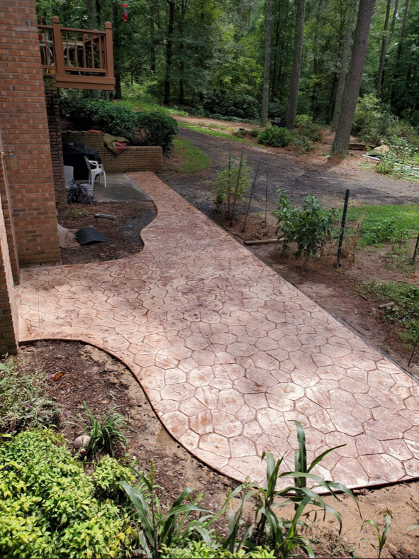 A concrete walkway leading to a house in the woods.