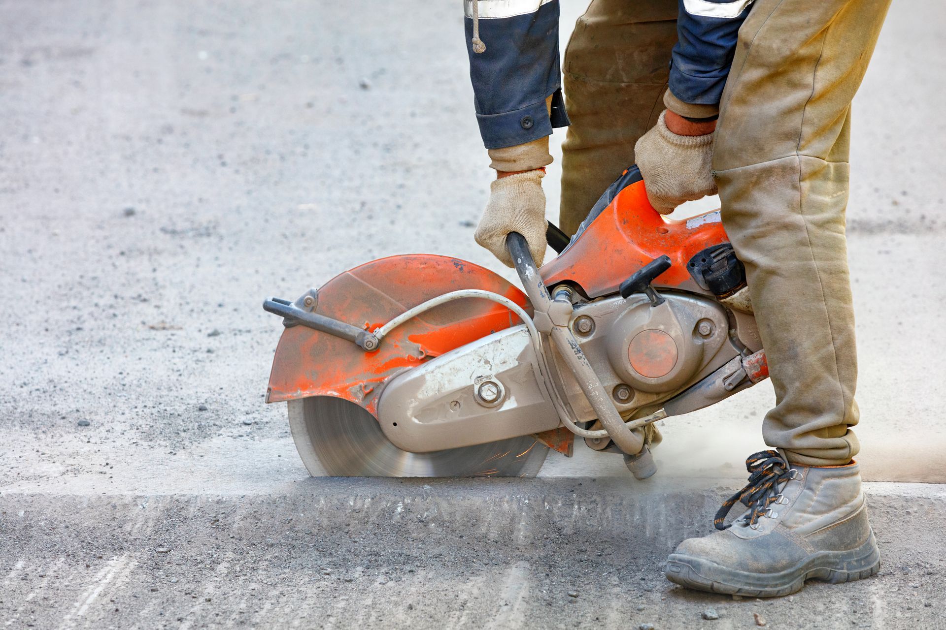 A man is using a circular saw to cut concrete.