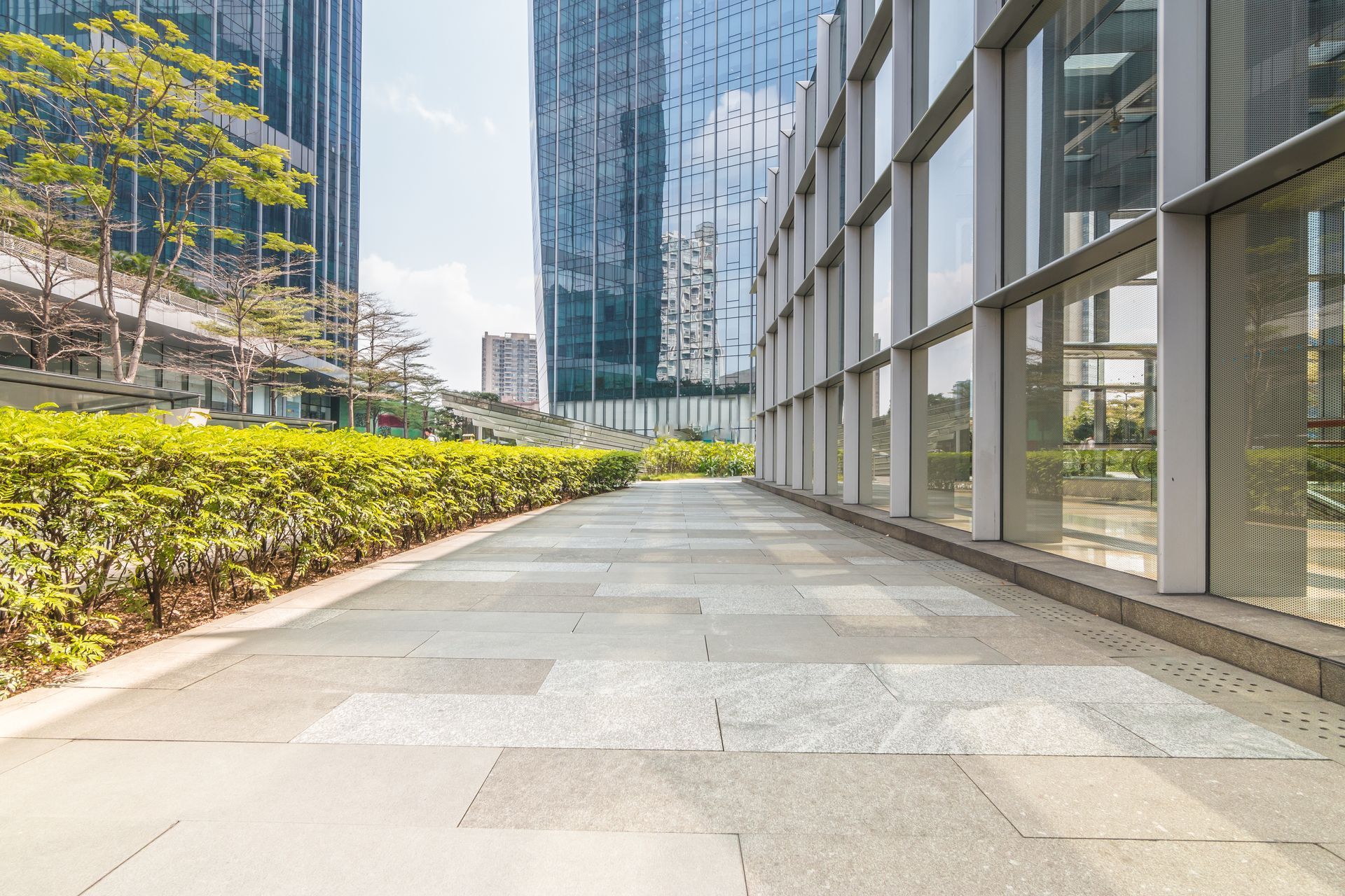 An empty walkway in front of a tall building with lots of windows.