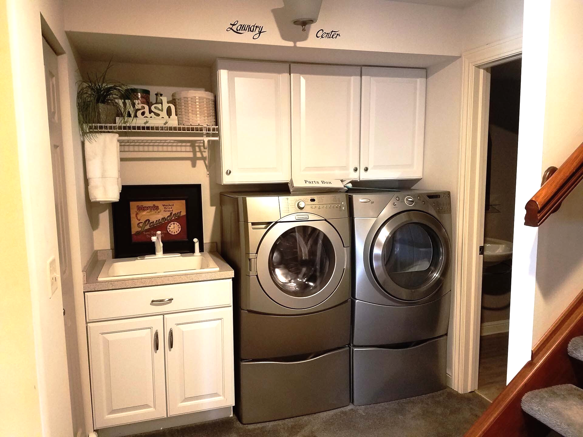Laundry room remodeling  with white cabinets, appliances, and a sink. Silver washer/dryer.