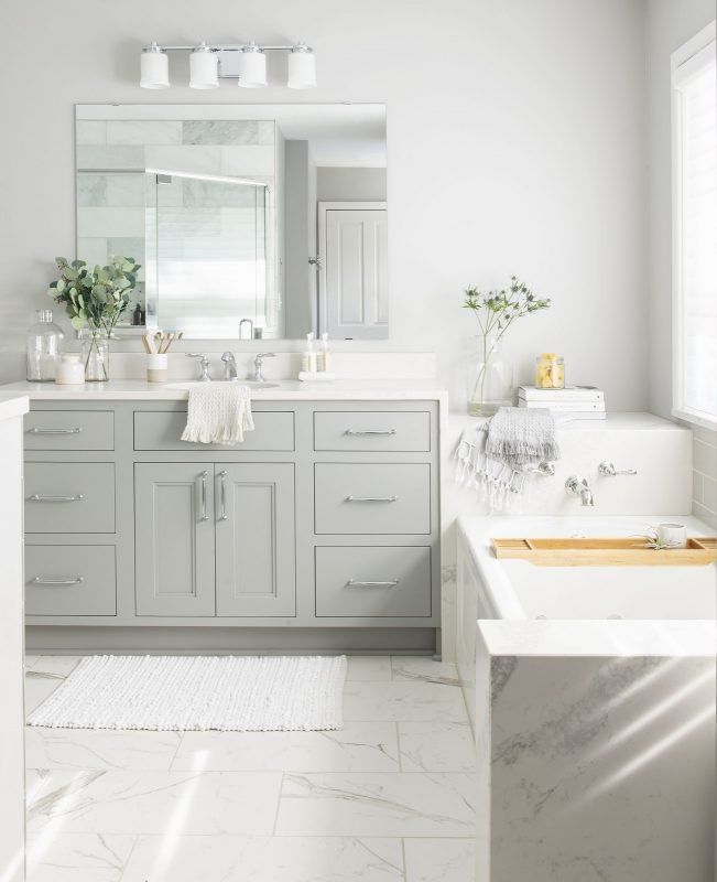 Light gray bathroom with a vanity, bathtub, and large mirror; bright, airy.