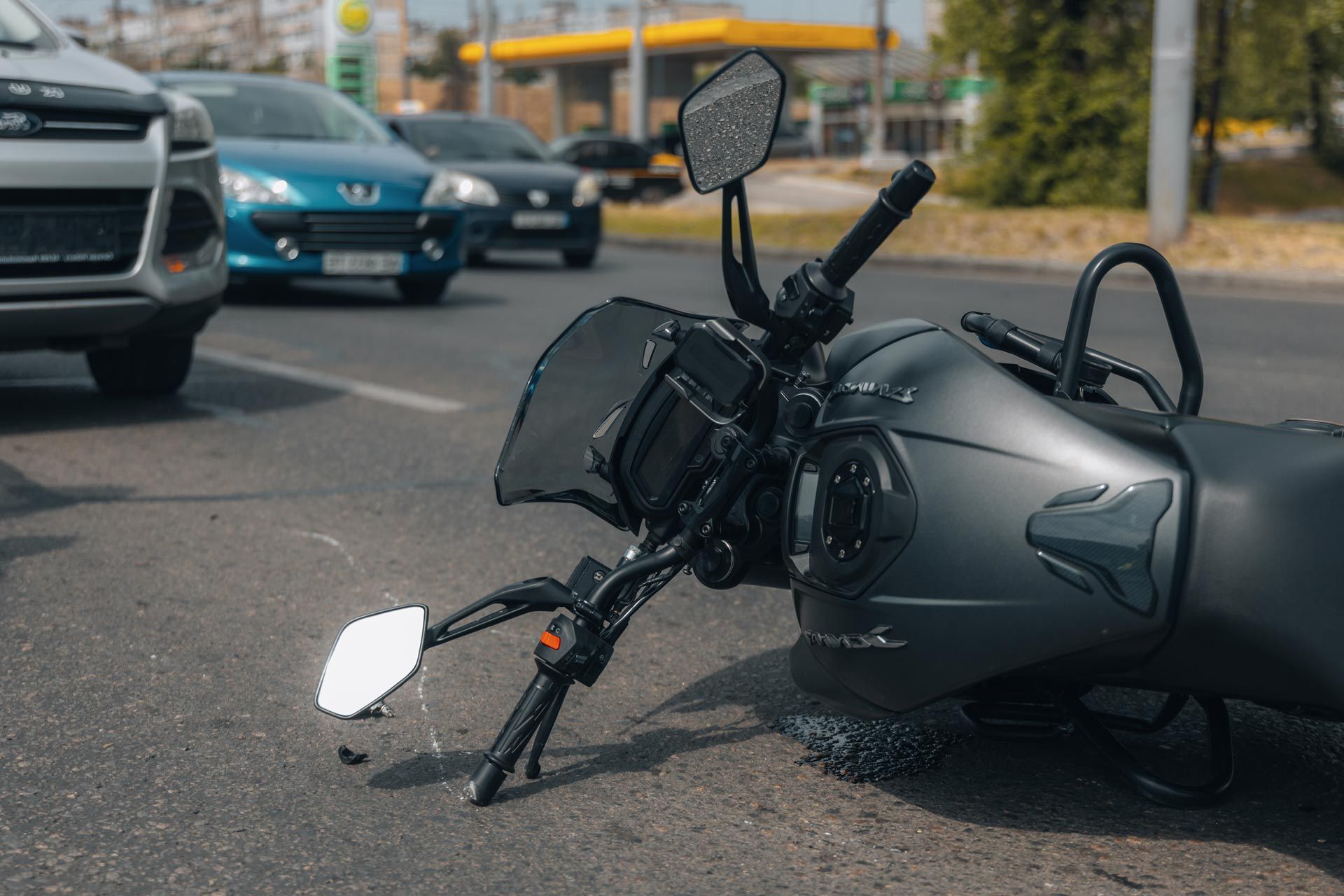 Motorcycle accident with bike lying on roadway amid traffic.