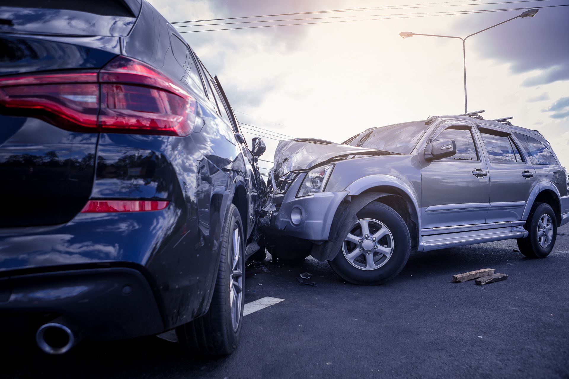Photograph showing a car accident involving two vehicles with front-end damage on a paved road under