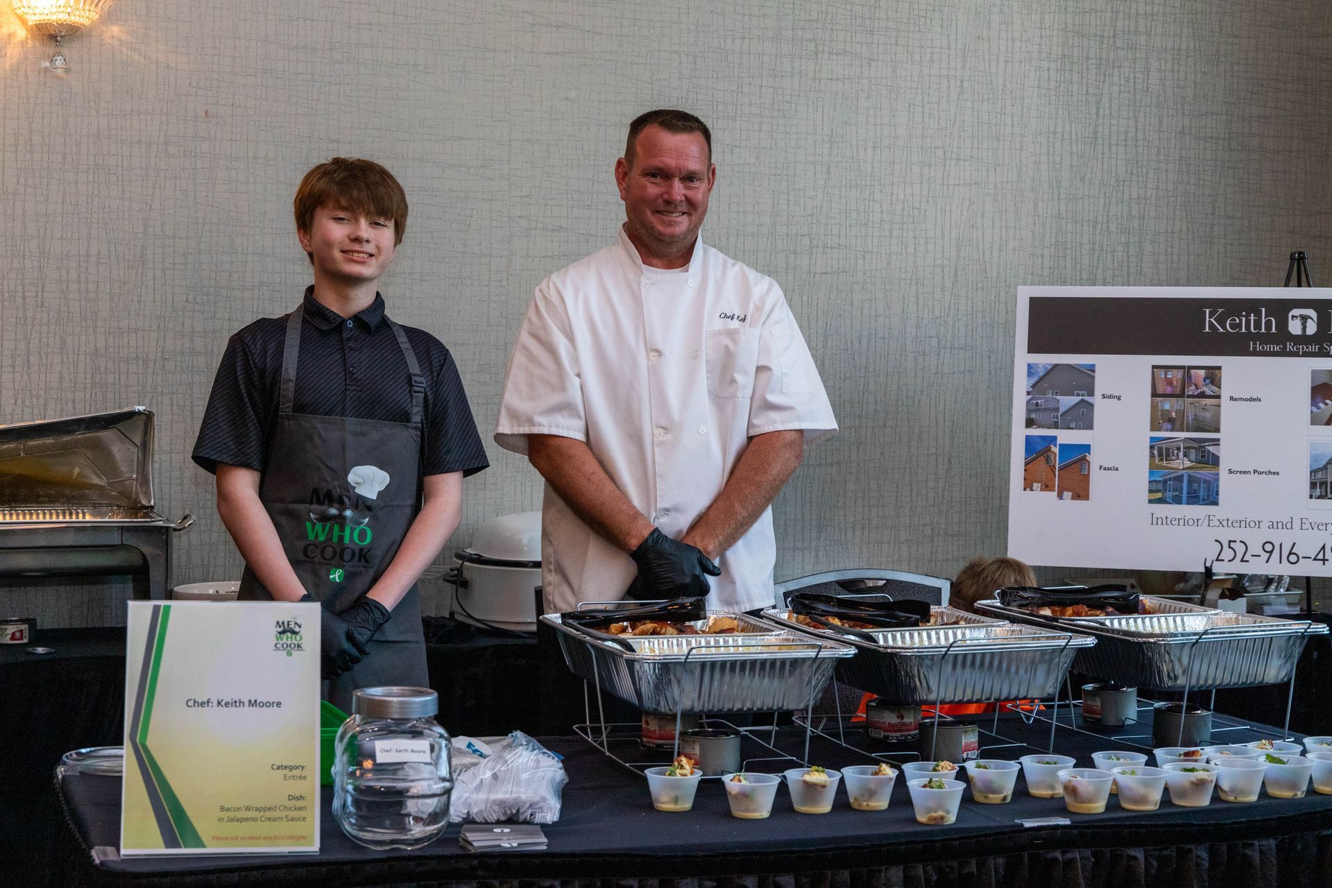 a man and a boy are standing in front of a buffet table .