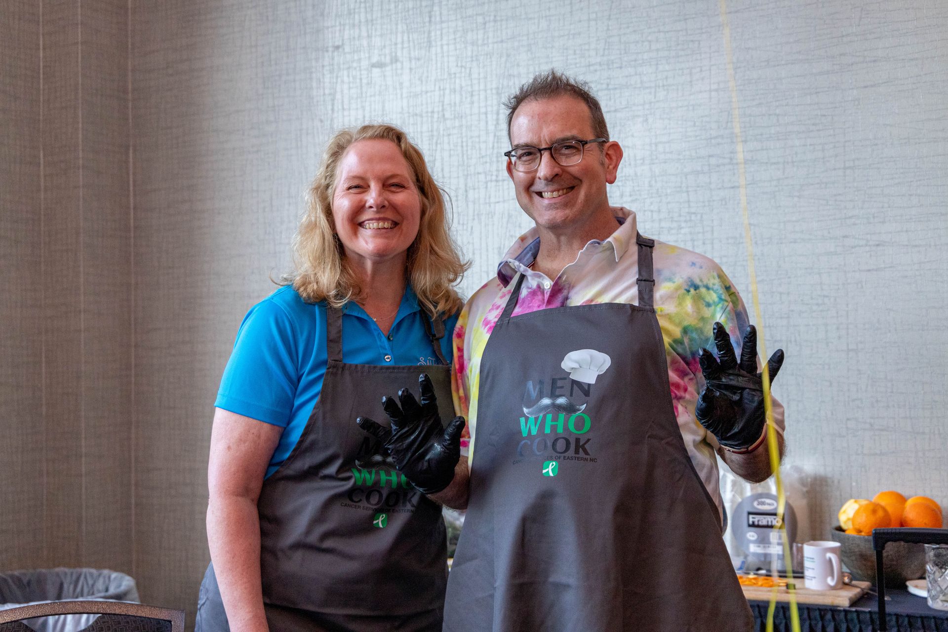 a man and a woman wearing aprons are posing for a picture .