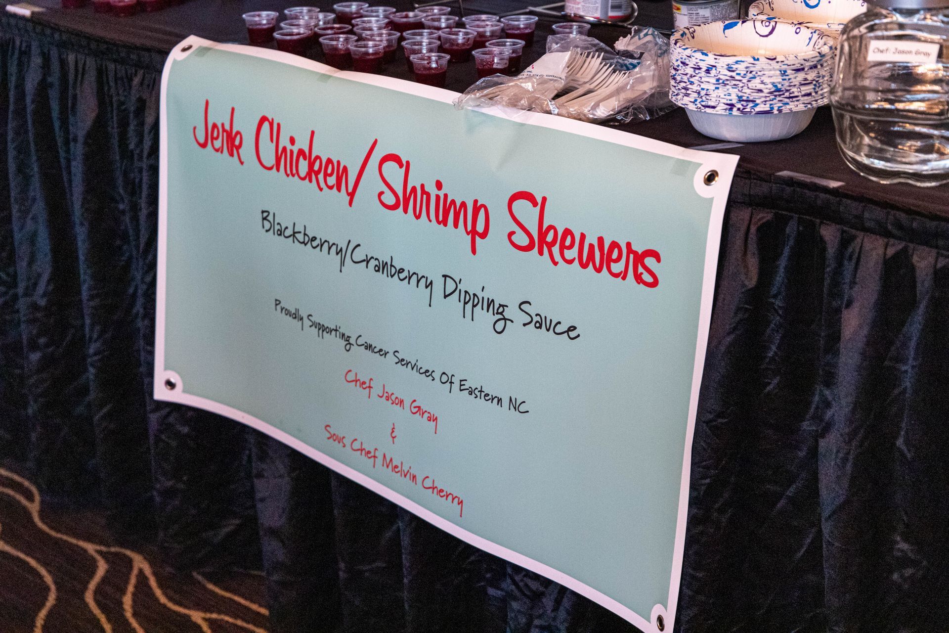 a table with a sign that says jerk chicken shrimp skewers