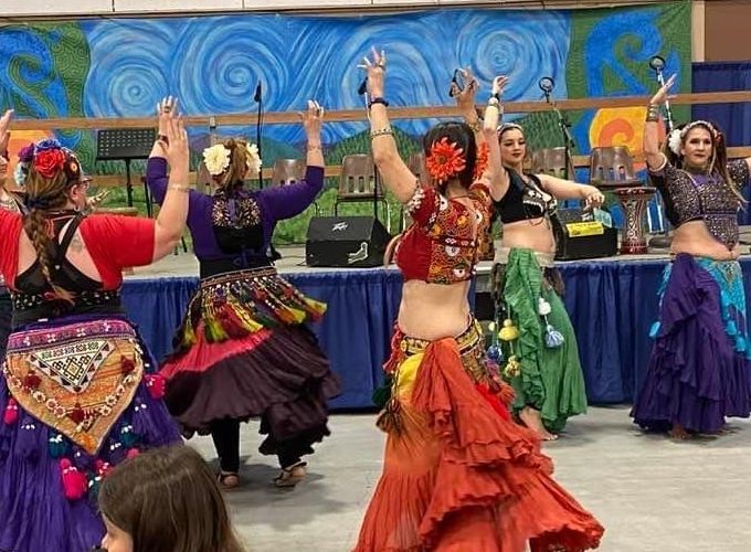 Several dancers swirl in colorful skirts with arms raised