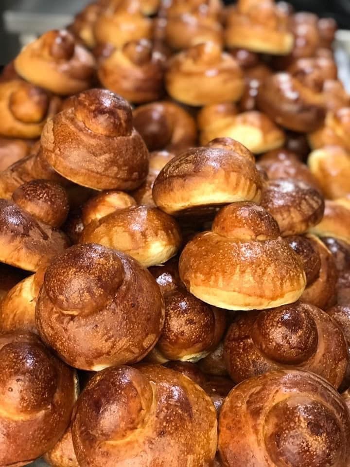Una grande pila di brioche appena sfornate, dorate e con la parte superiore arrotondata e sovrapposta.