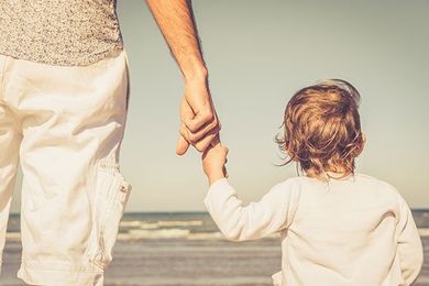 Father's hand lead his child son in summer beach