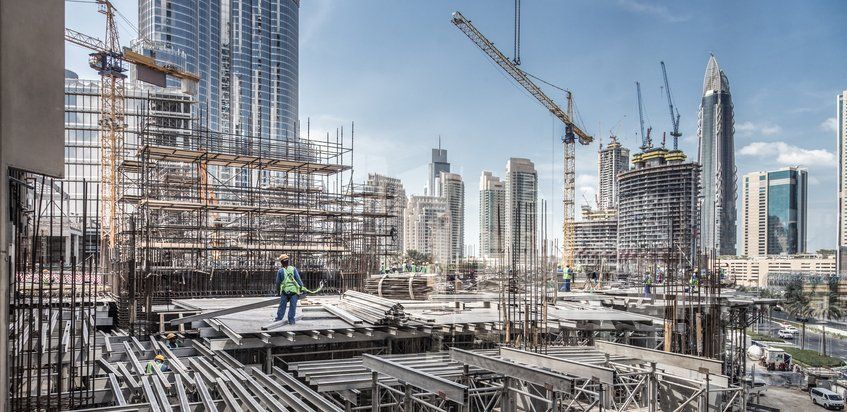 Laborers working on modern constraction site works in Dubai. Fast urban development consept