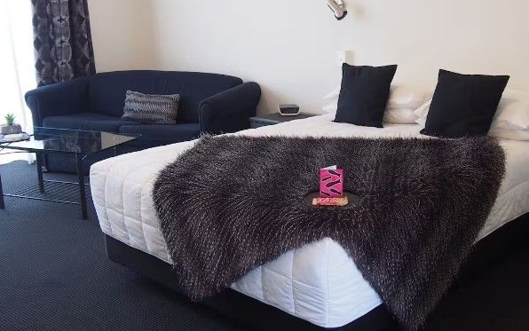 Hotel room with a bed covered in a fur blanket and a dark blue couch.