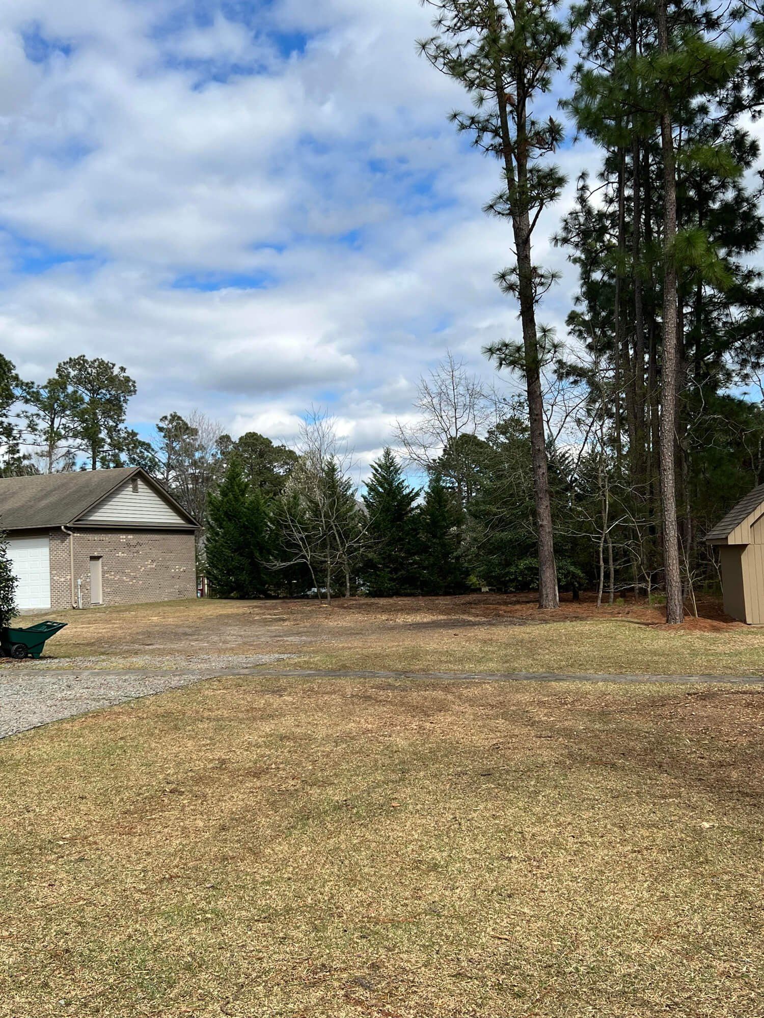 There is a house in the background and a lot of trees in the foreground.