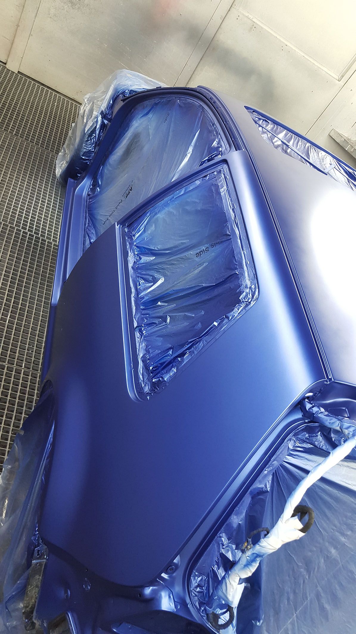 Ein Teil eines Autos ist gerade für die Lackierung mit Folie abgeklebt.