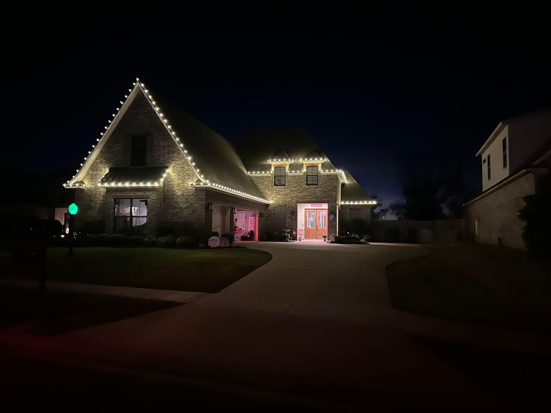A large house is lit up with christmas lights at night.