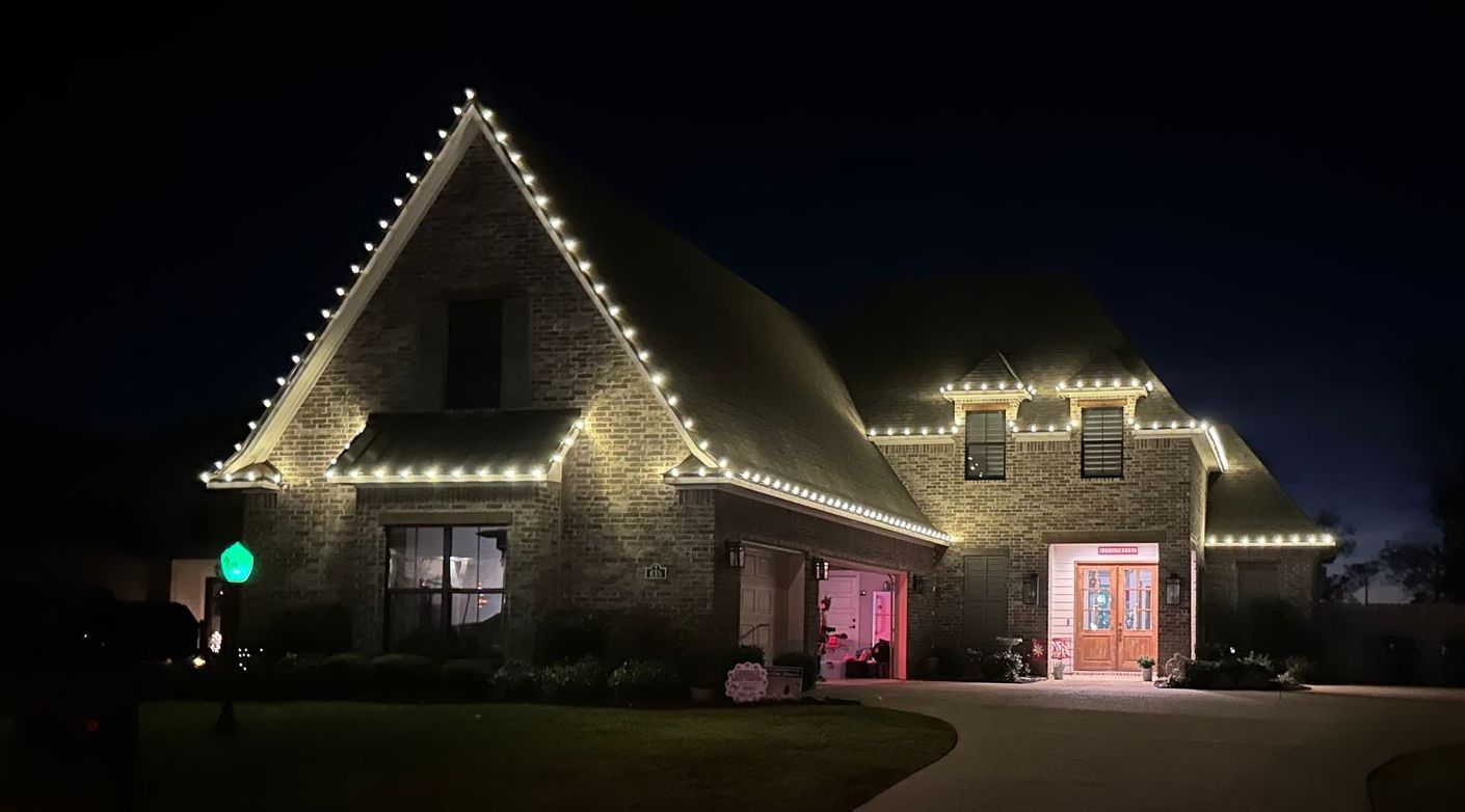 A large brick house is lit up with christmas lights at night.