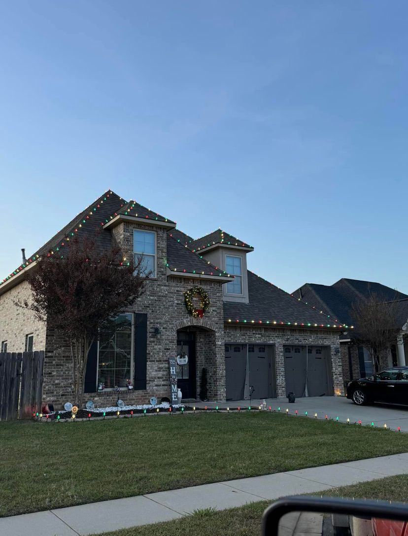 A large house with a wreath on the front of it, showcasing the holiday lighting