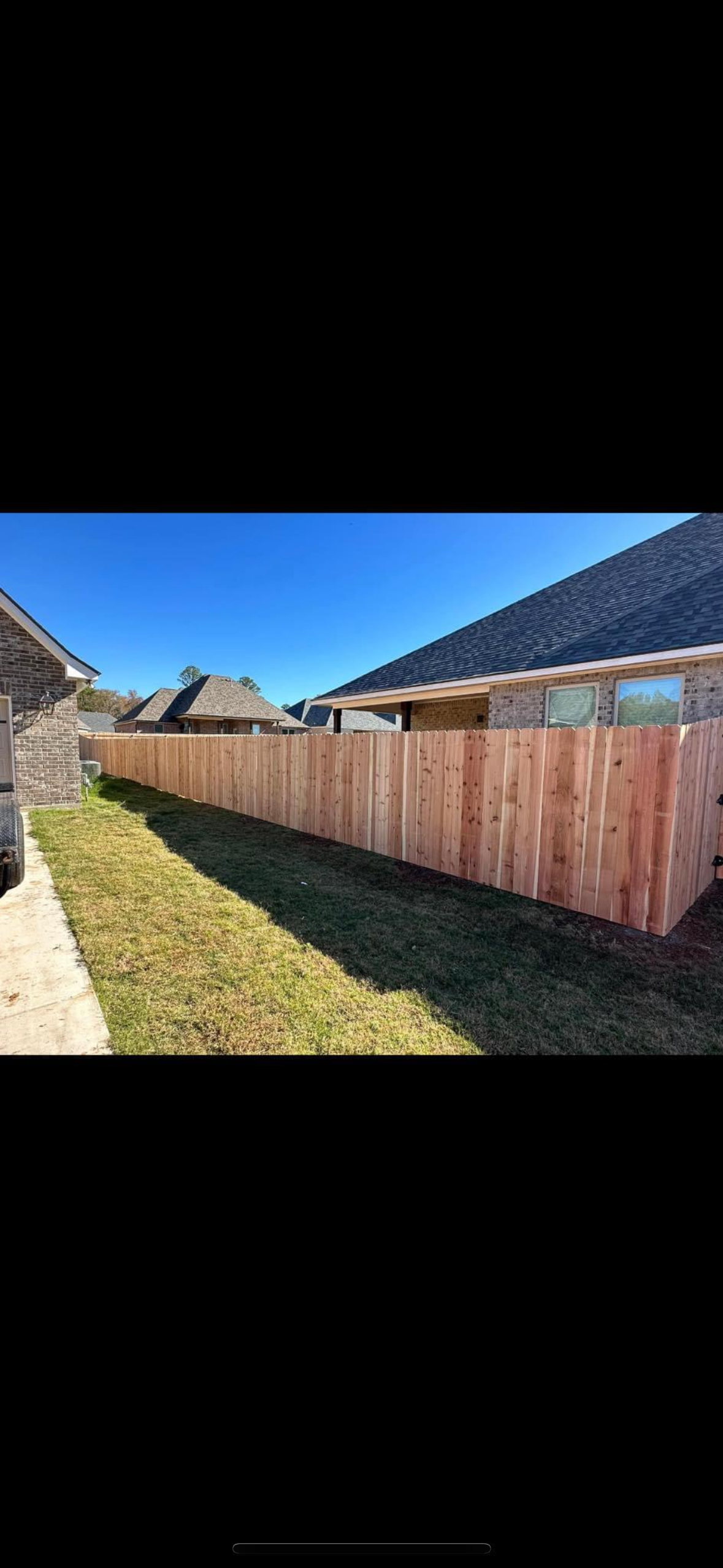 A wooden fence is sitting in the grass in front of a house.
