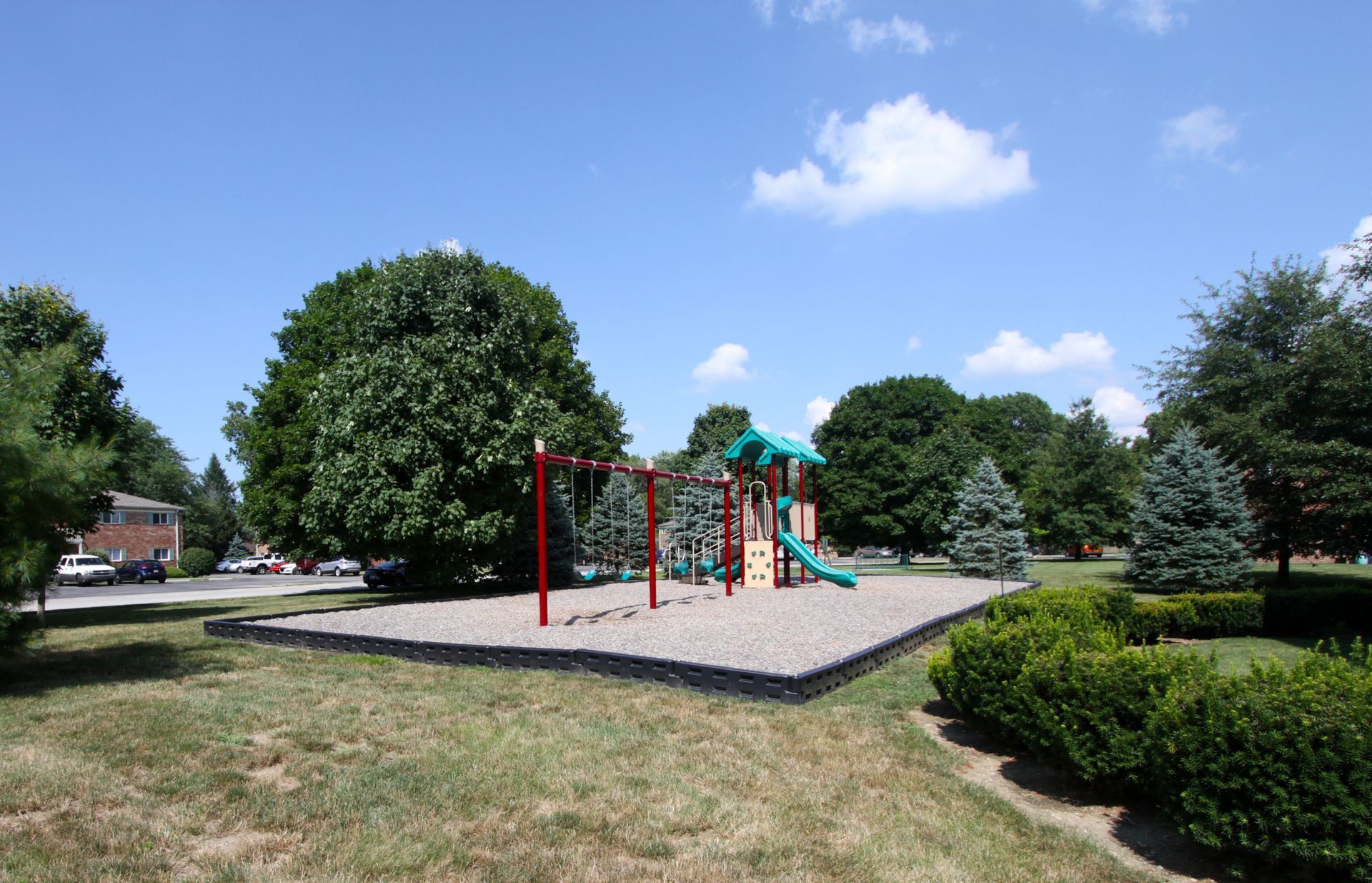 A park with a playground and trees on a sunny day