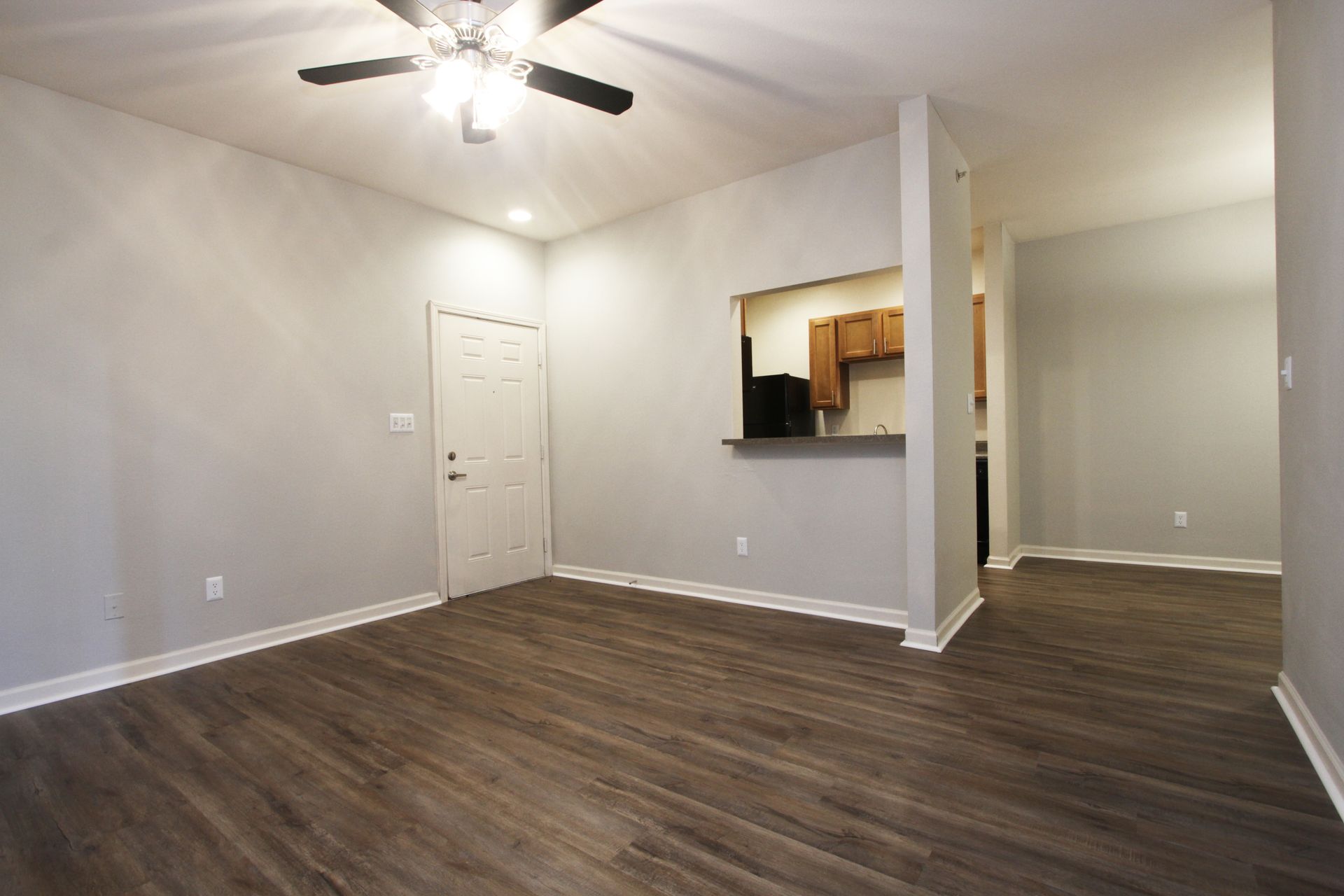 An empty living room with hardwood floors and a ceiling fan.