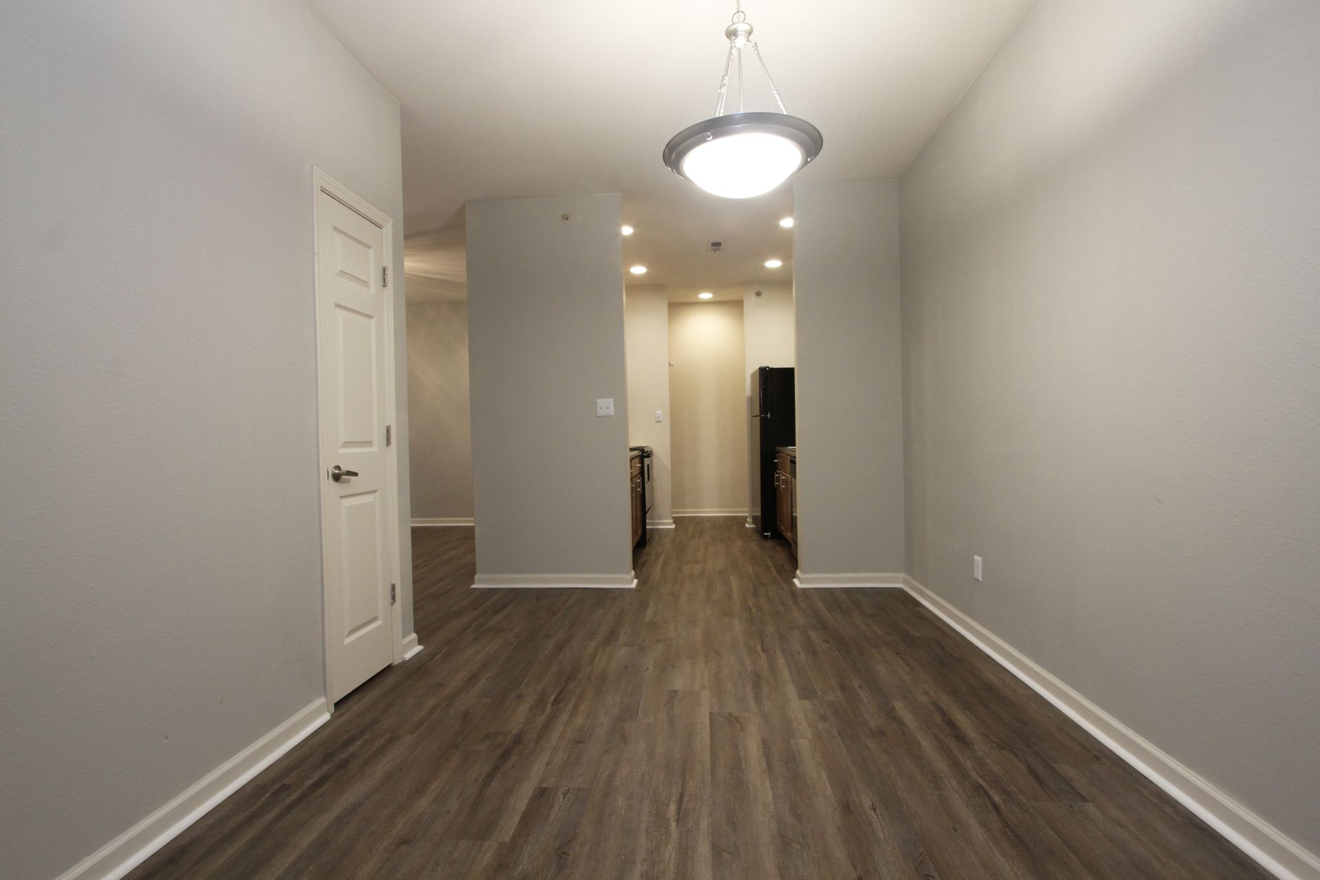 An empty dining room with hardwood floors and a chandelier.