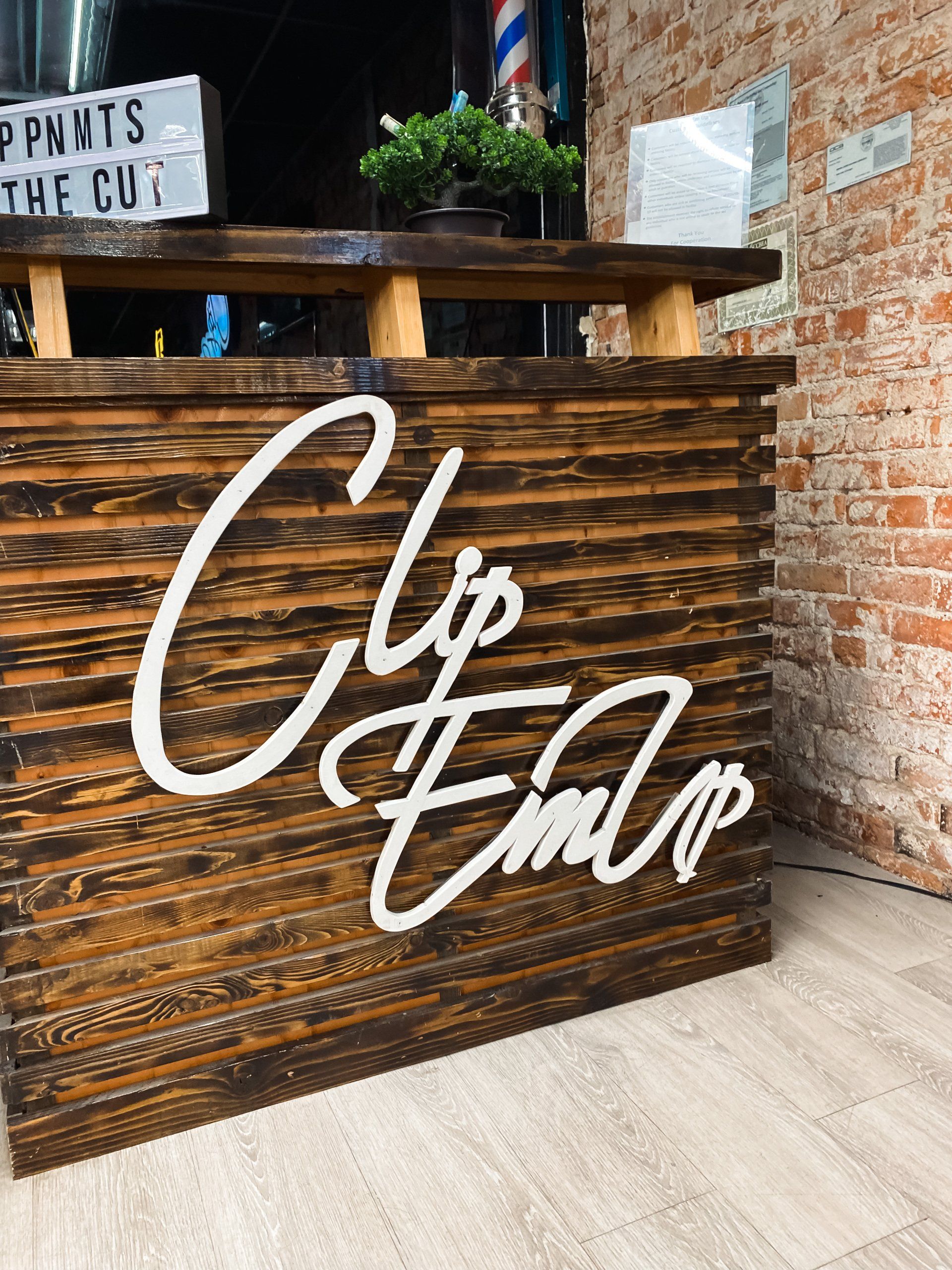 Wooden sign of Clip Em' Up logo