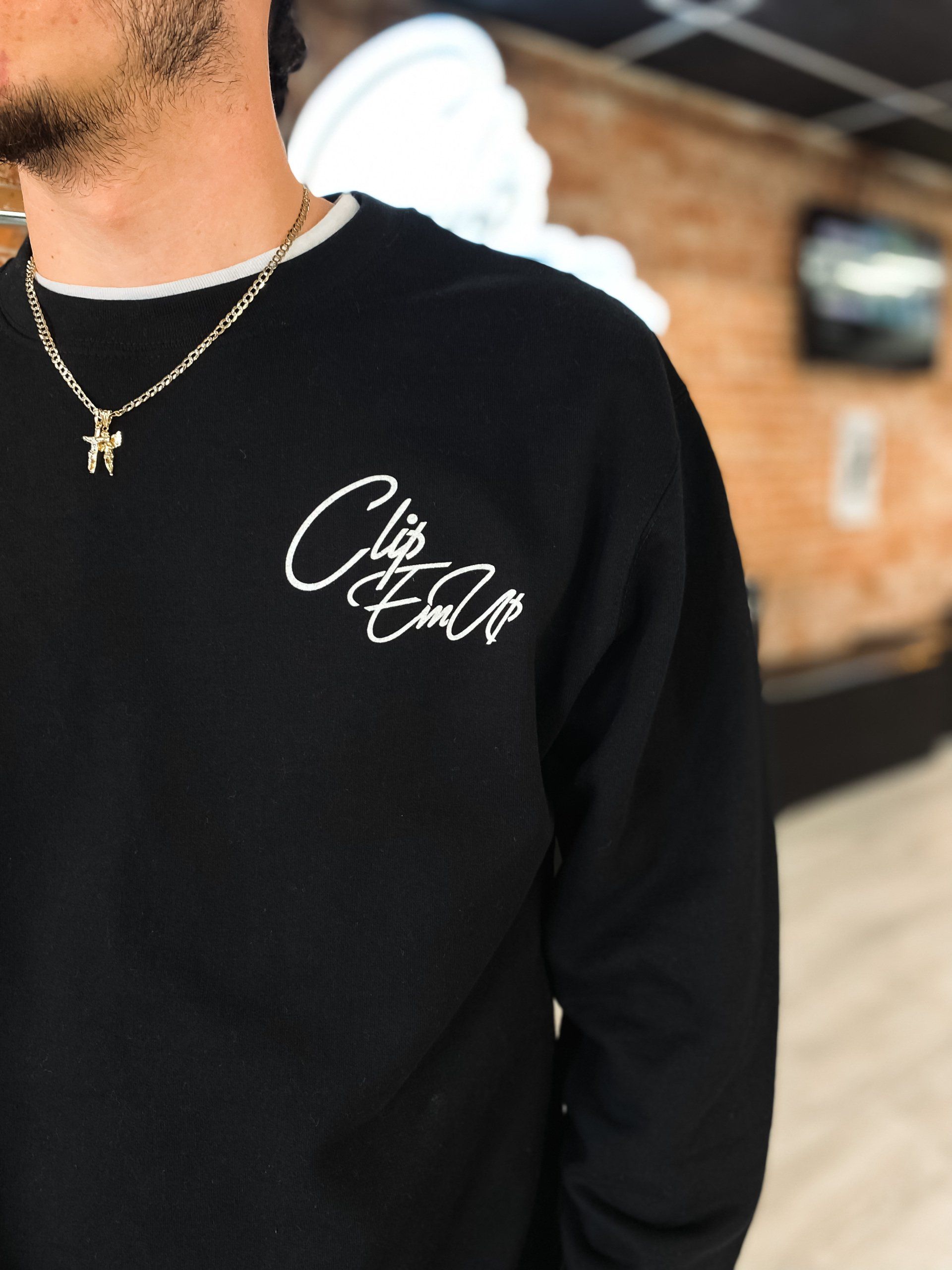 Black crewneck with Clip Em' Up staple logo