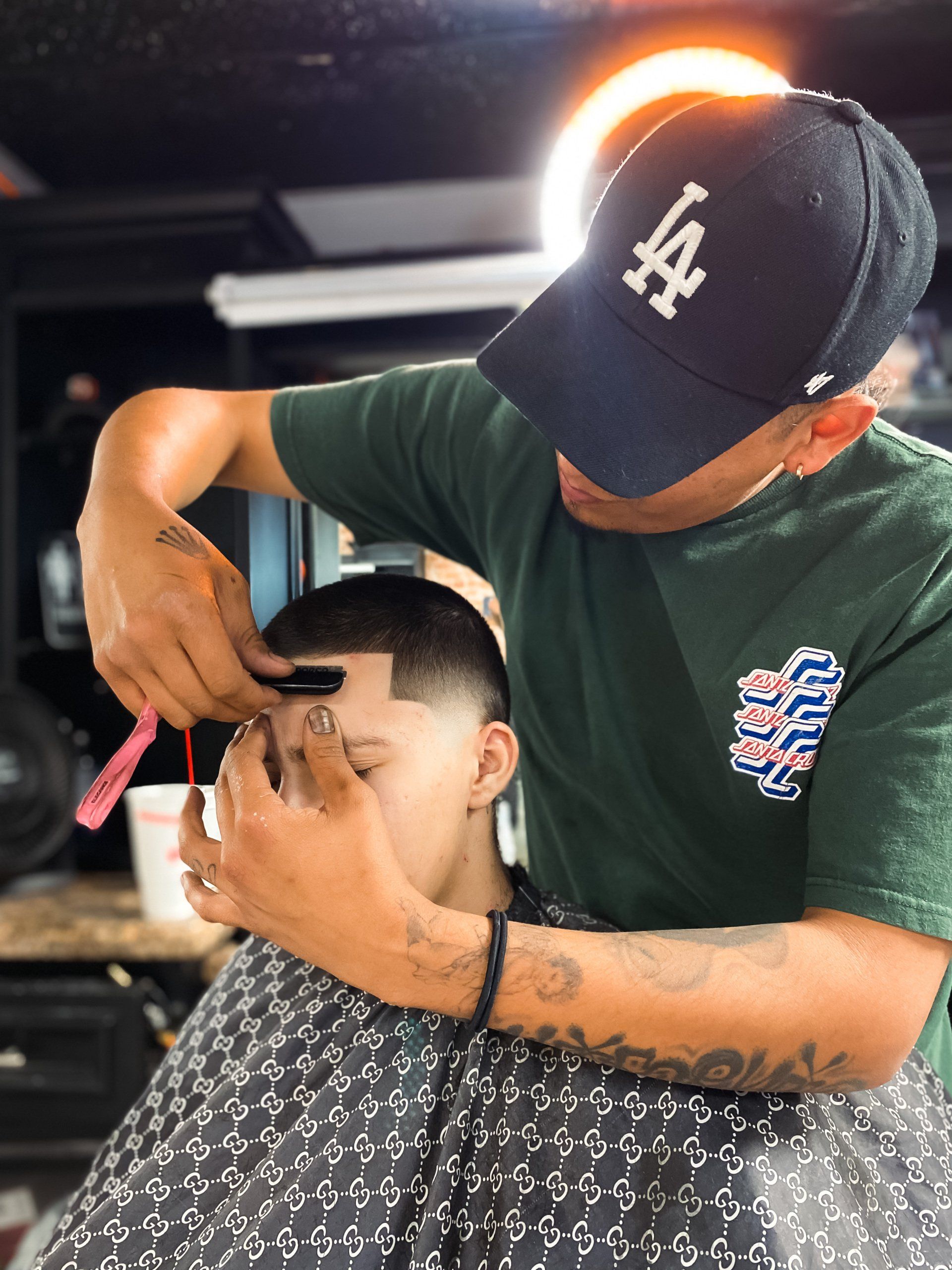 Barber Gio at Clip Em' Up using razor to line up hair