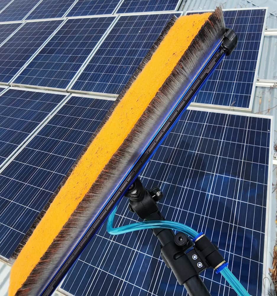 A Person Cleaning Solar Panels With a Long-handled Brush and Water Hose — Rapid Rinse Solutions in Katunga, VIC