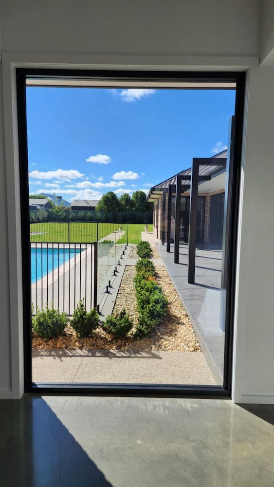 View Through a Window of a Pool and Backyard on a Sunny Day — Rapid Rinse Solutions in Cobram, VIC
