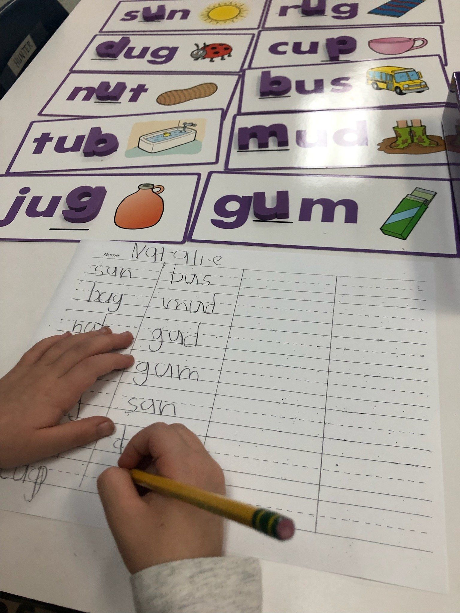 A child is writing on a piece of paper with a pencil