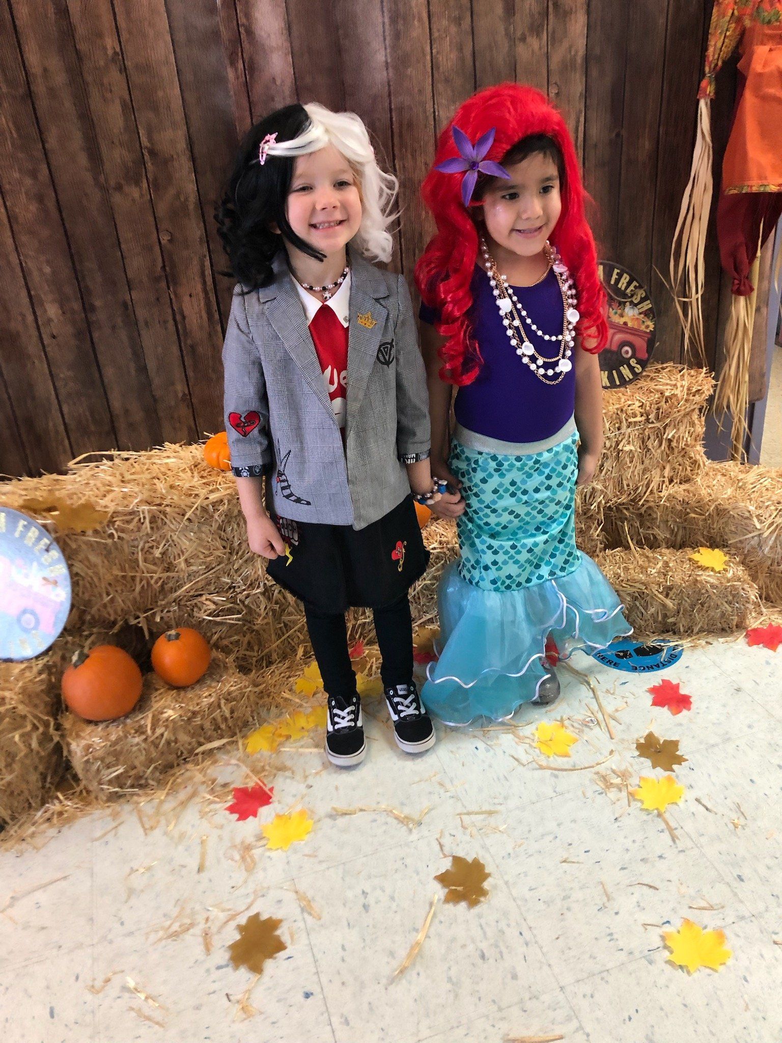 Two little girls in halloween costumes are standing next to each other.