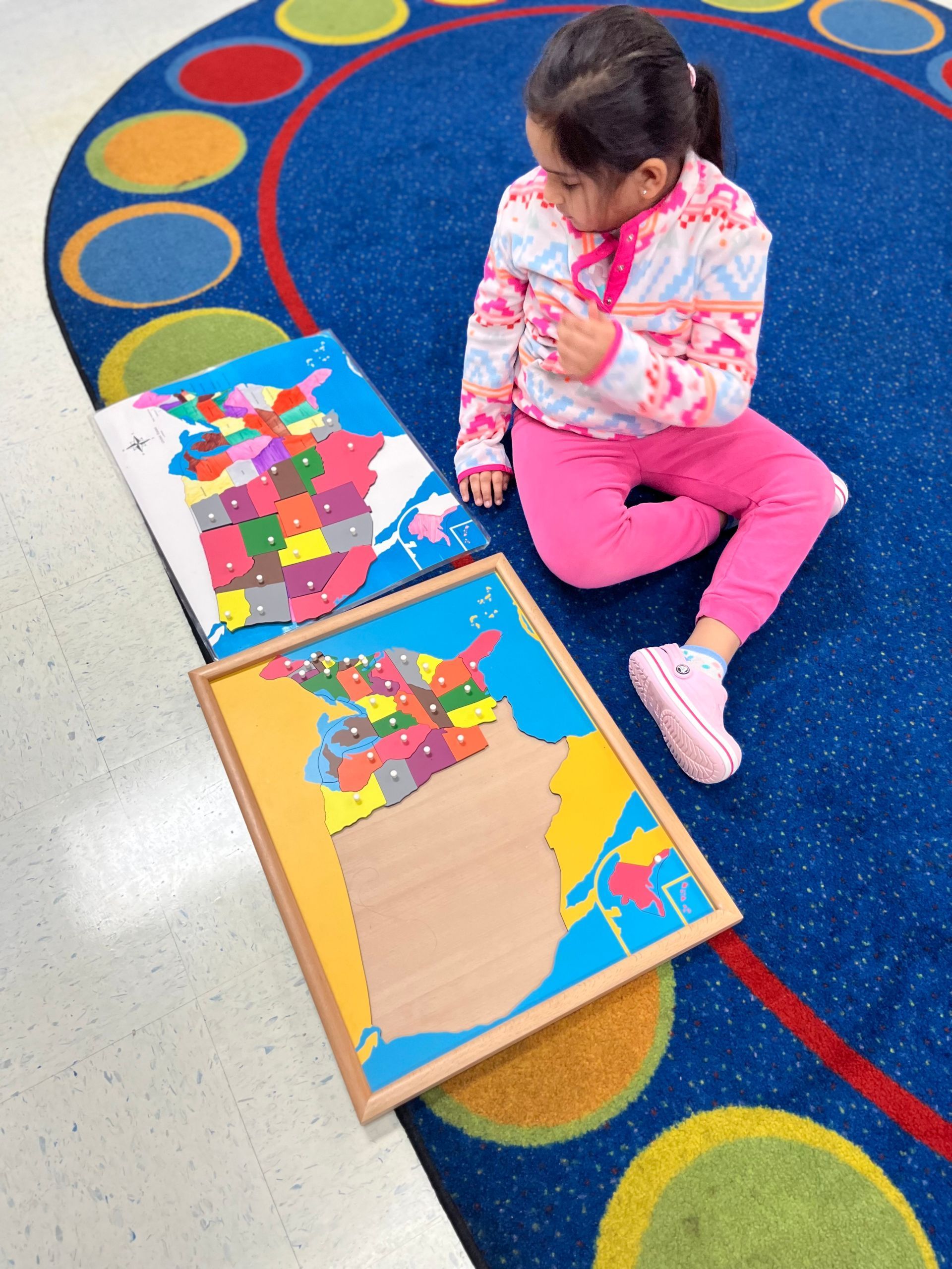 A little girl is sitting on the floor playing with maps