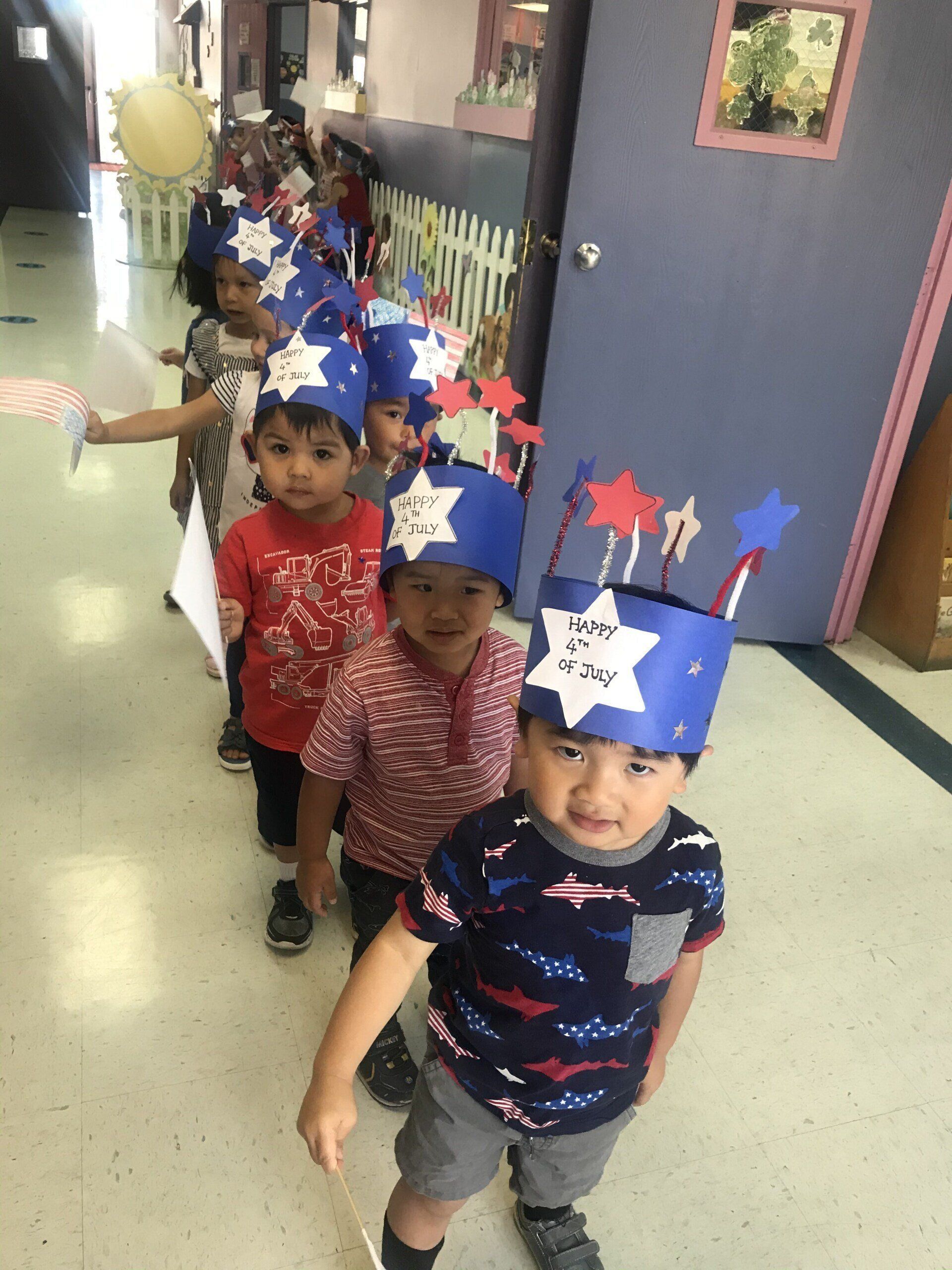 A group of children wearing patriotic hats are walking down a hallway.
