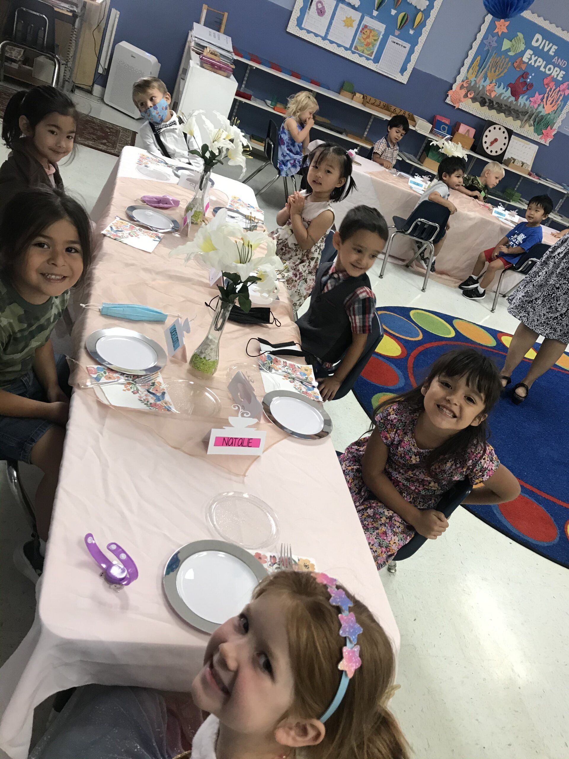 A group of young girls are sitting at a table with plates on it.