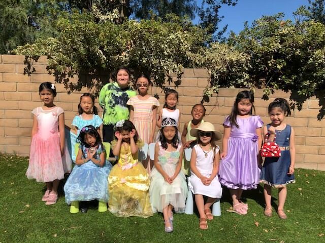 A group of young girls dressed as princesses are posing for a picture.