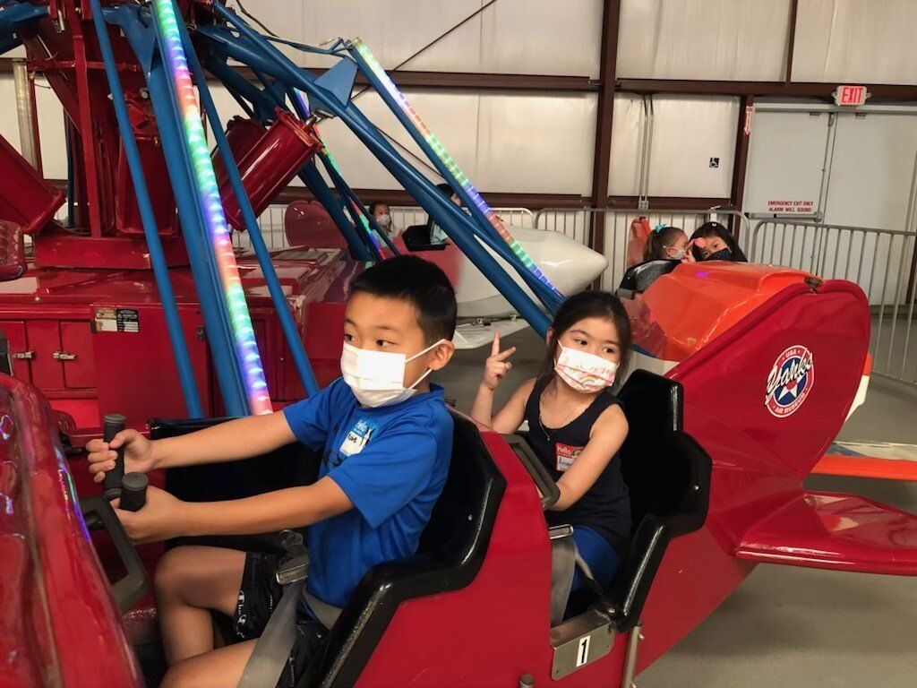A boy and a girl wearing face masks are riding a roller coaster.