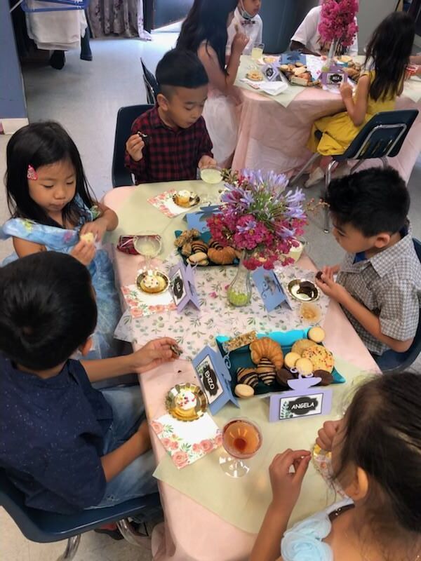 A group of children are sitting at a table eating food.