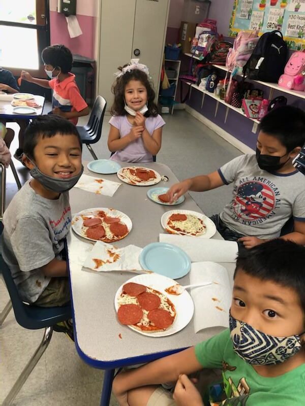 A group of children are sitting at a table with plates of pizza.