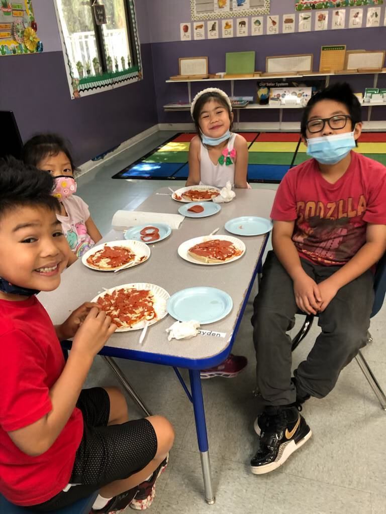 A group of children are sitting at a table eating pizza.