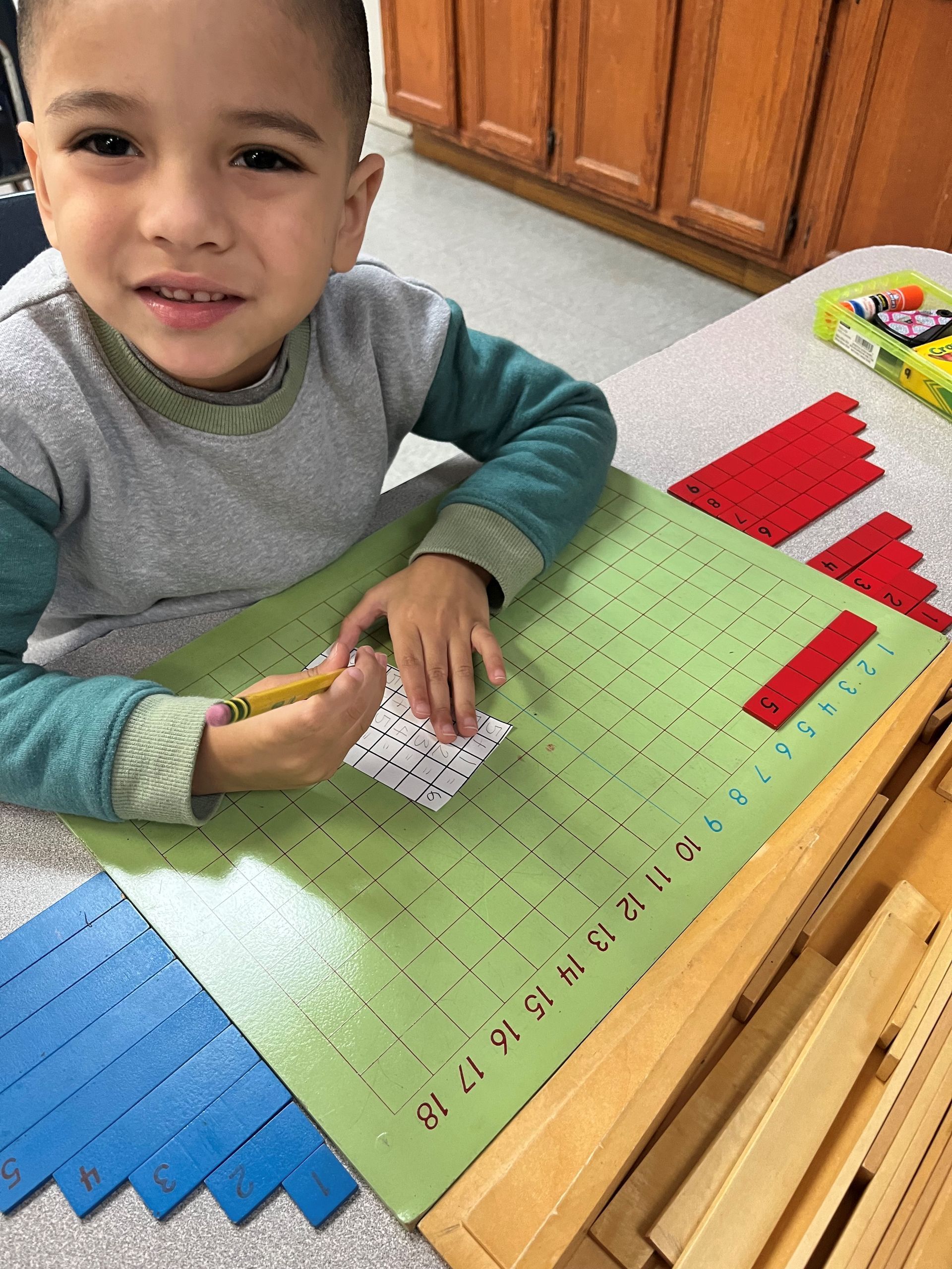 A young boy is sitting at a table writing on a piece of paper.