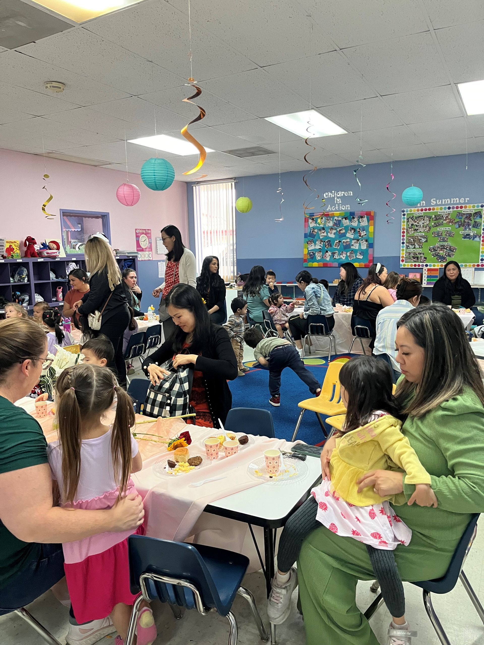 A group of people are sitting at tables in a room with balloons hanging from the ceiling.
